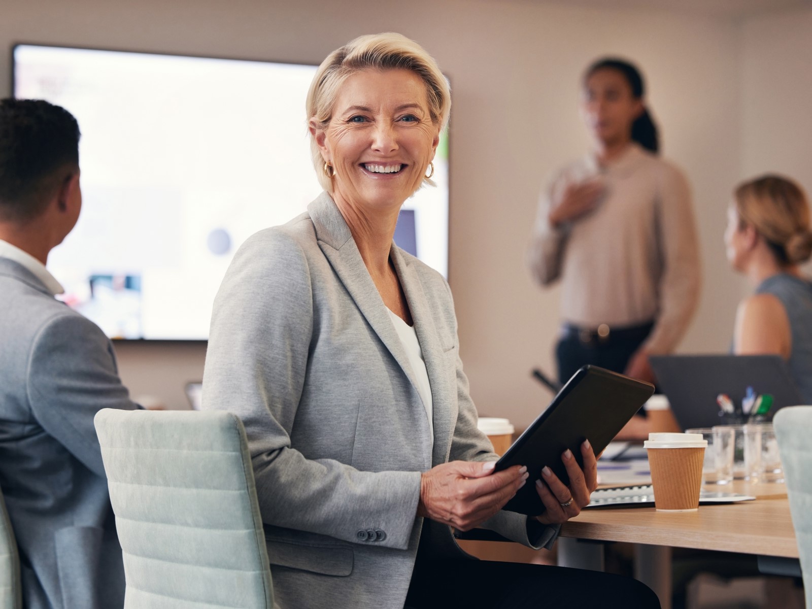 Kvinnlig företagare i mötesrum, tittar leende mot kamera