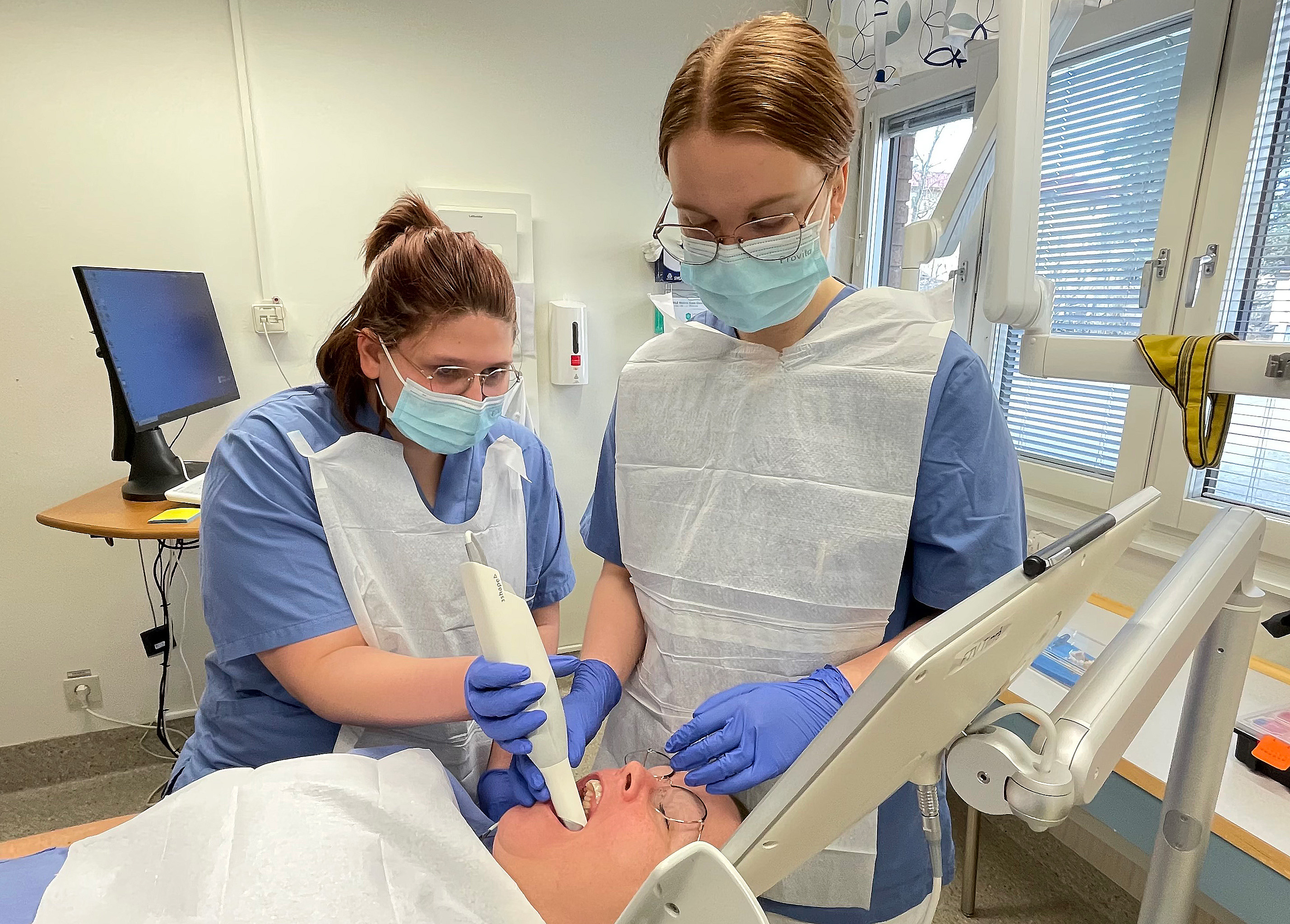 Tandläkare Matilda Nyman visar Ordelya Wasén Wiklund hur man scannar tänder på studie- och yrkesvägledare Ingela Antonsson, som fick agera patient.
