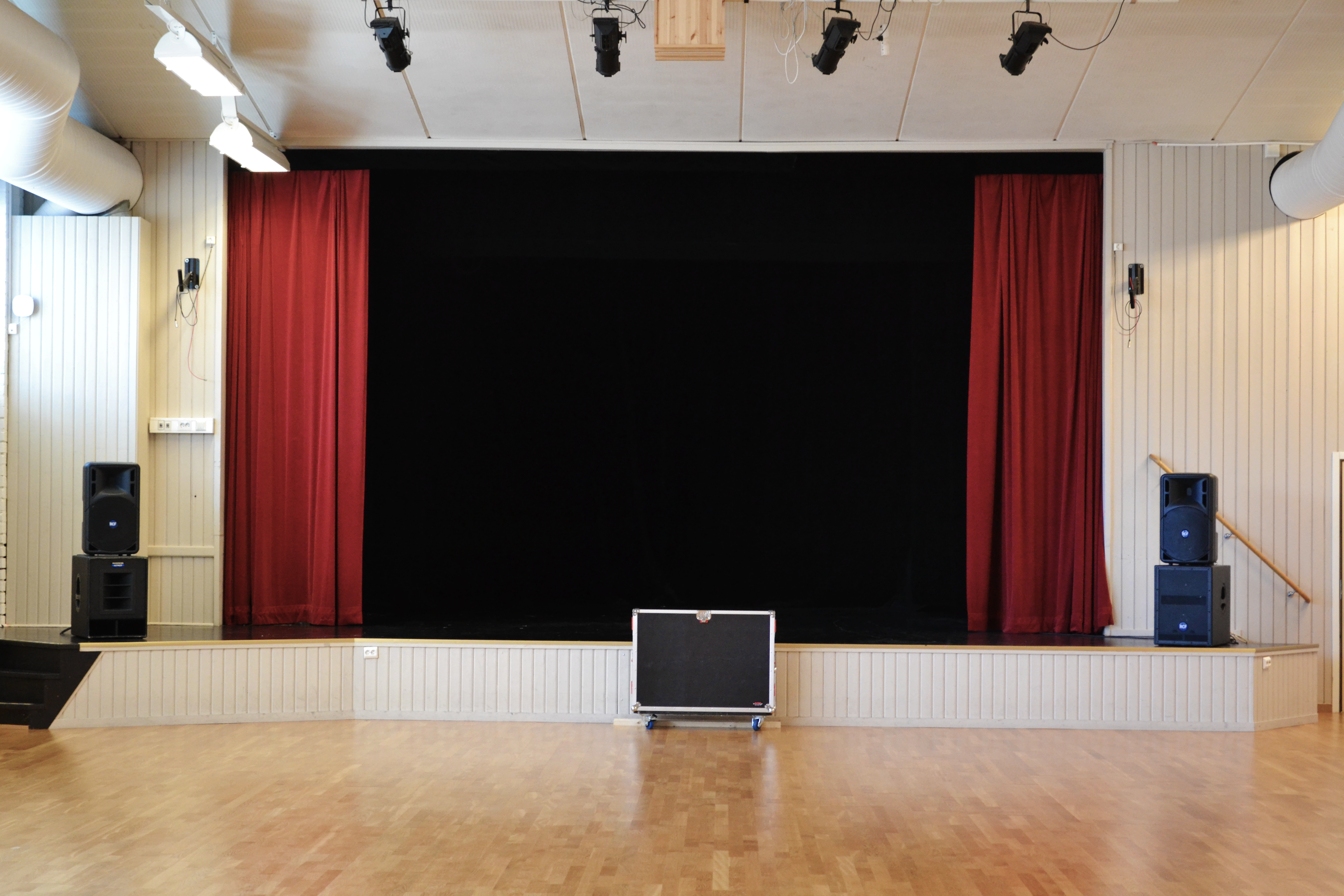 Överblicksbild över eventhallen med scen, ljudanläggning och blankt trägolv