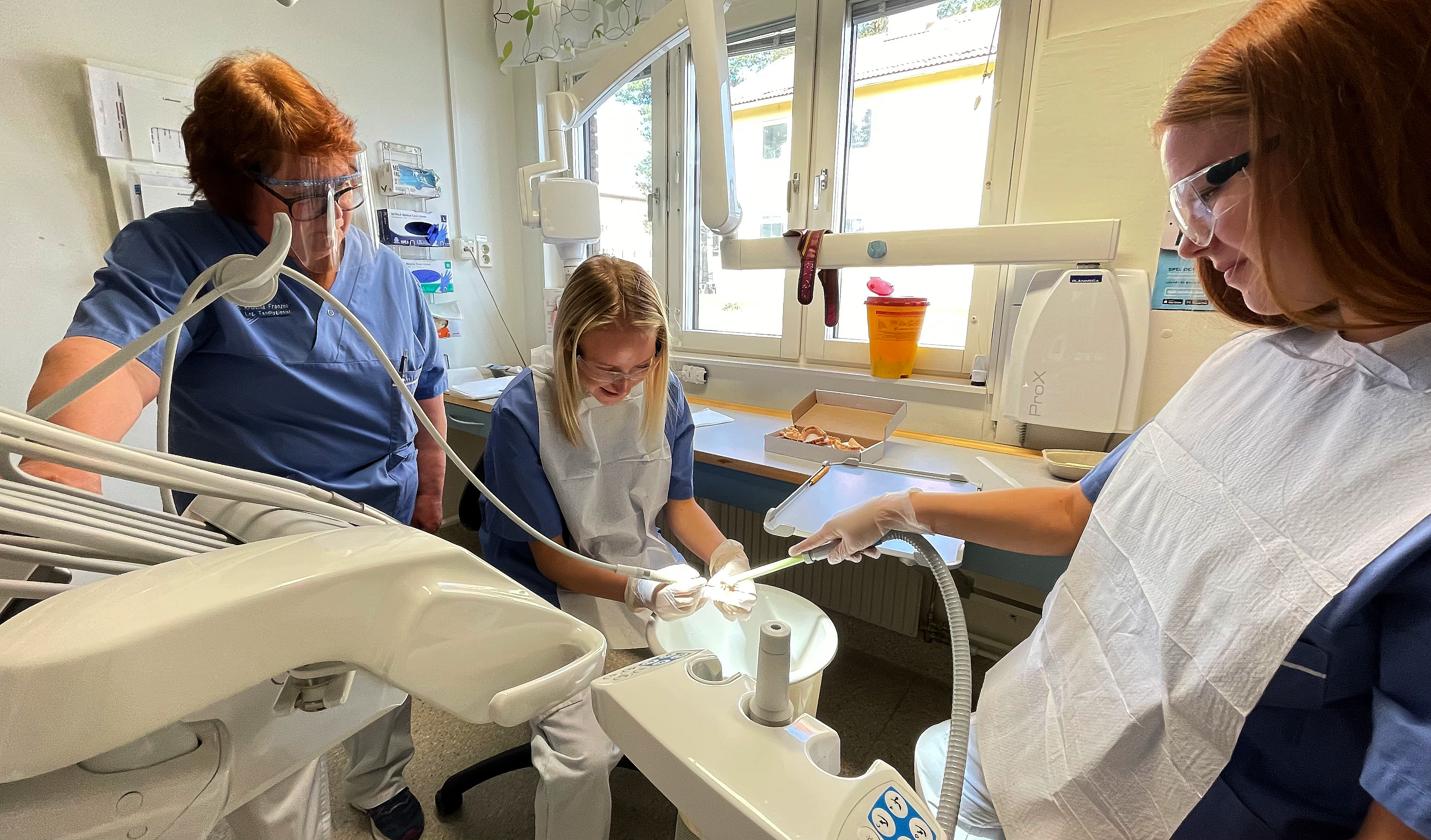 Tandhygienist Kristina Franzén hjälper Alva Biberg och Minna Westén när de provar att ta bort tandsten från plasttänder.